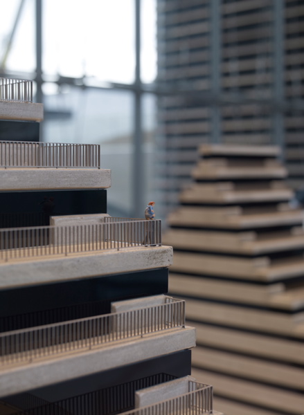 Au premier plan et à gauche, on voit une partie du haut d'un des volumes, qui consiste en des terrasses minitatures. Un personnage est sur une des terrasses, donnant une idée de l'échelle du volume. A l'arrière-plan et à droite, on voit une partie du second volume.